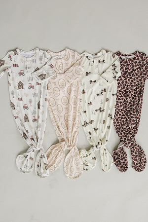 Four ribbed bamboo knot gowns in soft pastel colors, featuring playful patterns like tractors and animals, designed for babies. These eco-friendly garments offer comfort and easy diaper changes.