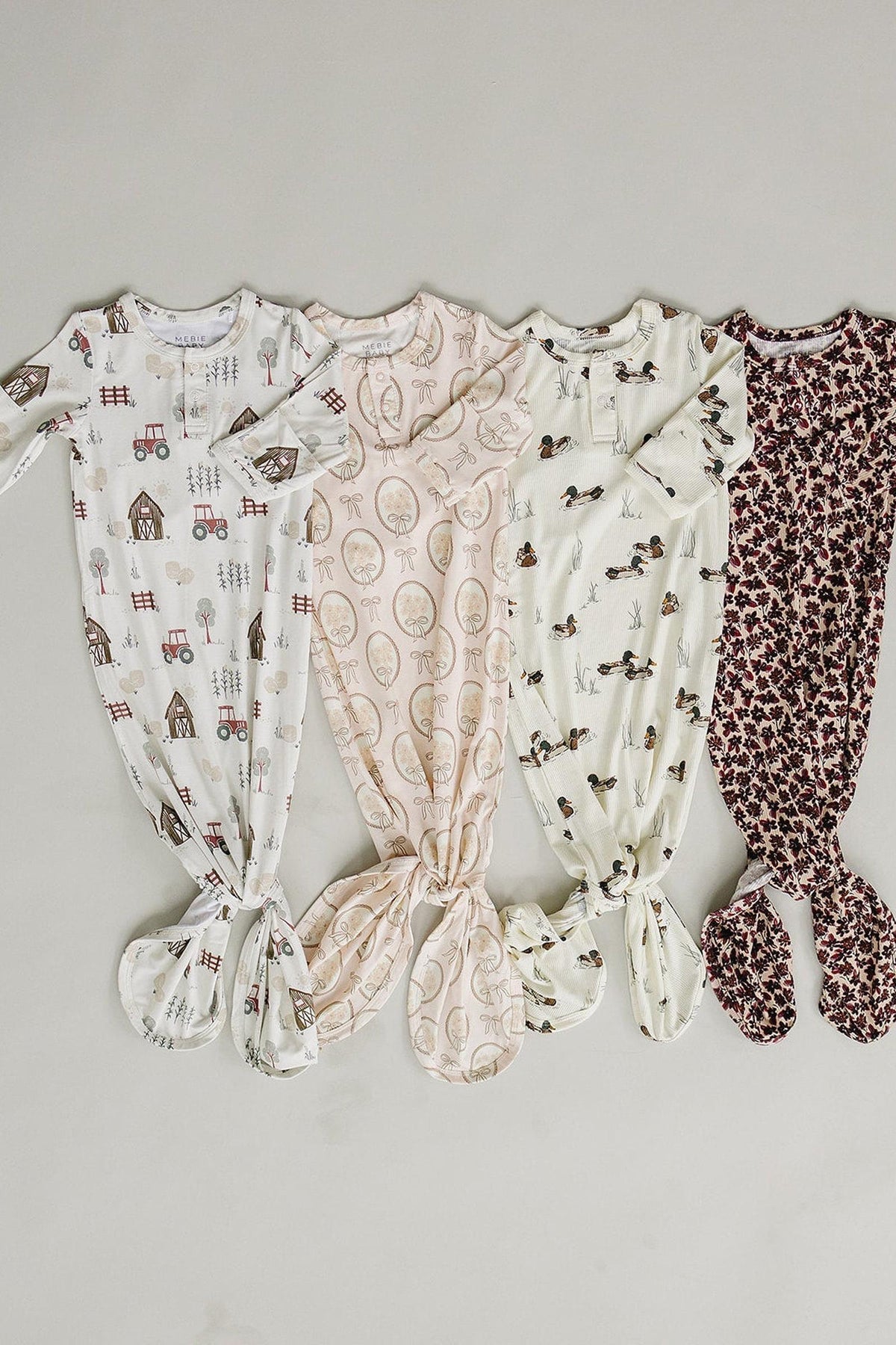 Four baby gowns made from soft, ribbed bamboo fabric feature different playful patterns, including farm themes and floral designs.