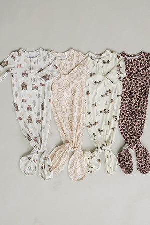 Four baby gowns made from soft, ribbed bamboo fabric feature different playful patterns, including farm themes and floral designs.
