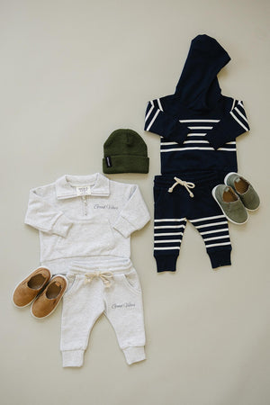 Grey quarter zip sweatshirt set and navy striped hoodie outfit, both with matching pants, shoes, and a green beanie.
