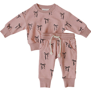 A blush pink French terry cotton set features a long-sleeve top with a bow print and matching sweatpants with a drawstring.