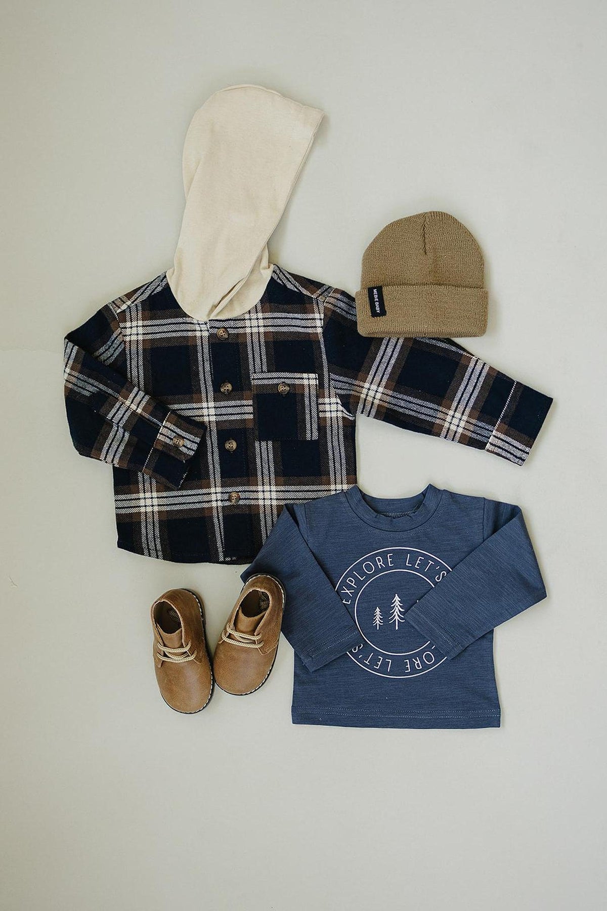 Plaid hooded button-up shirt with tan hood, blue graphic tee, brown boots, and a tan knit beanie.