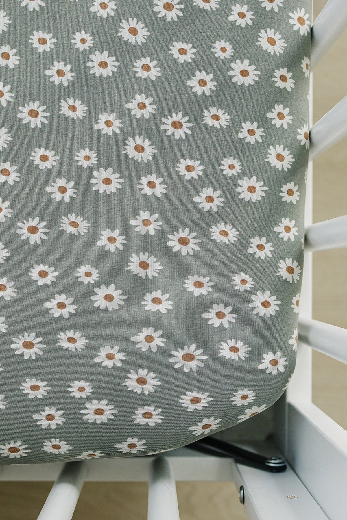 Light green crib sheet featuring a daisy pattern with white flowers and brown centers, designed for baby cribs.