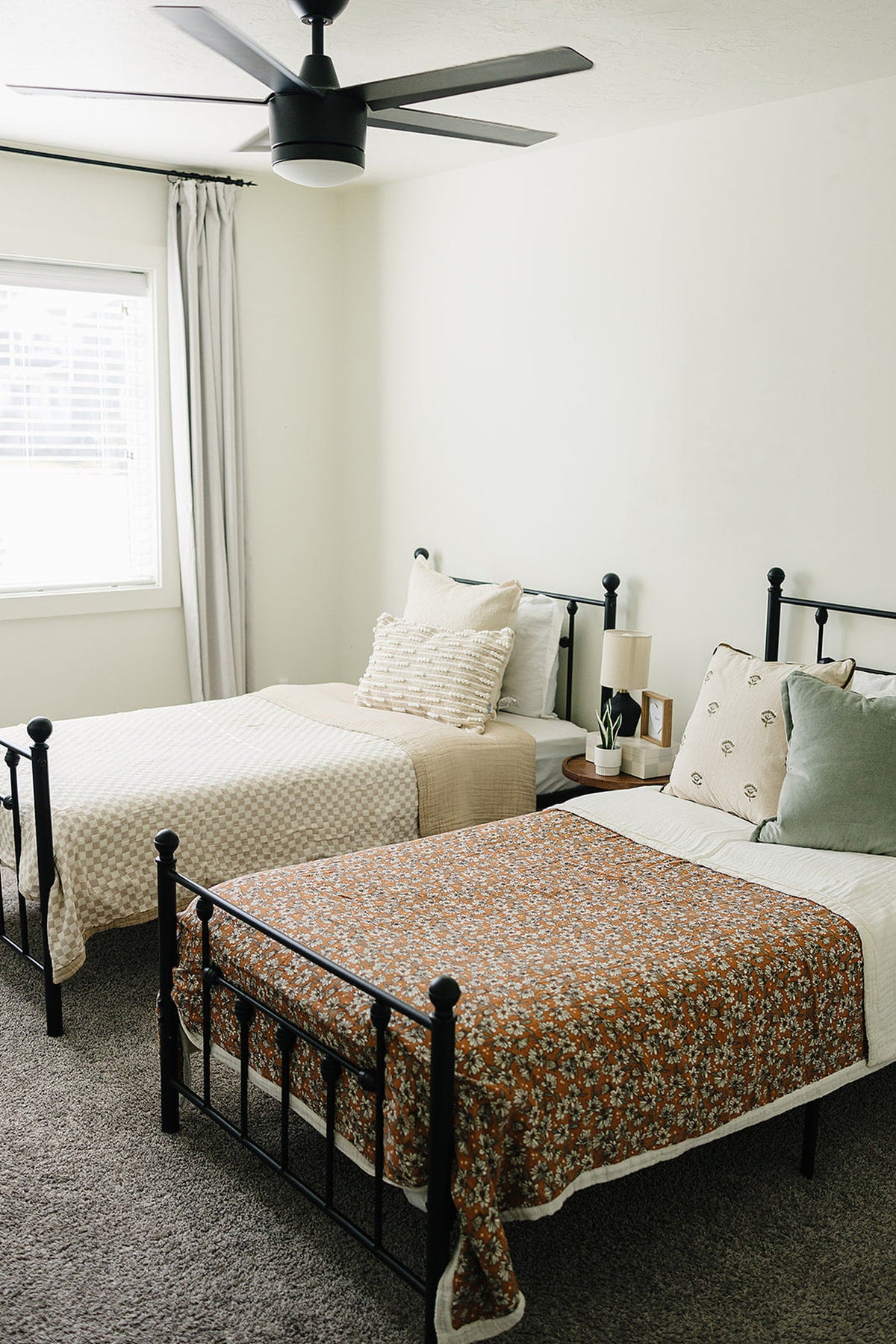 A cozy bedroom featuring two twin beds, one with a floral quilt and the other with a textured beige coverlet.