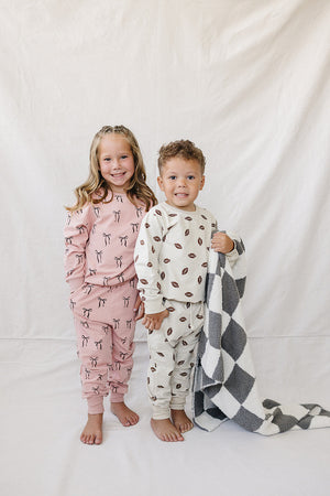 Two children stand together in front of a light backdrop, wearing matching sets of soft French terry cotton loungewear.