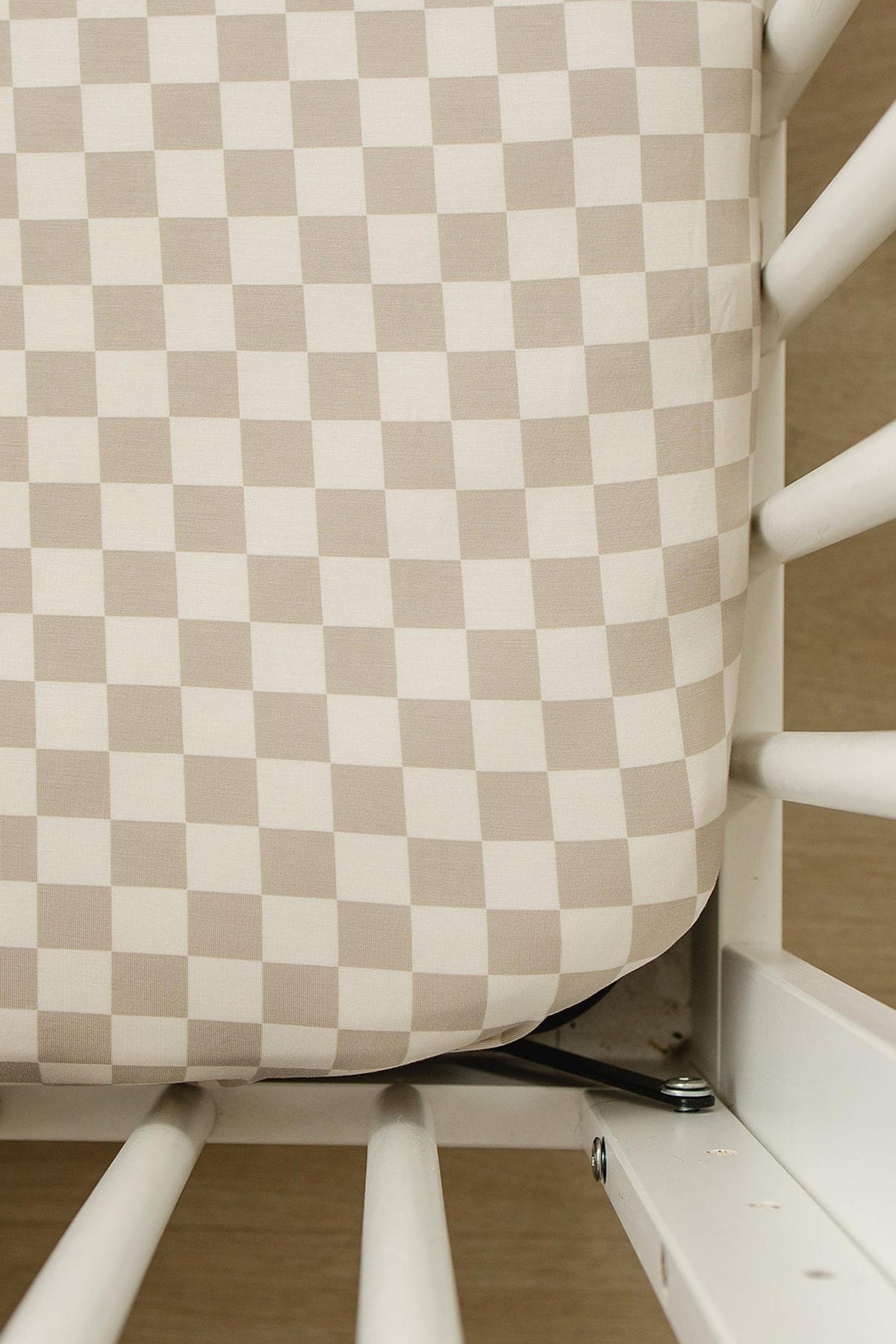 Taupe checkered crib sheet on a white crib, showcasing soft bamboo fabric and modern style.