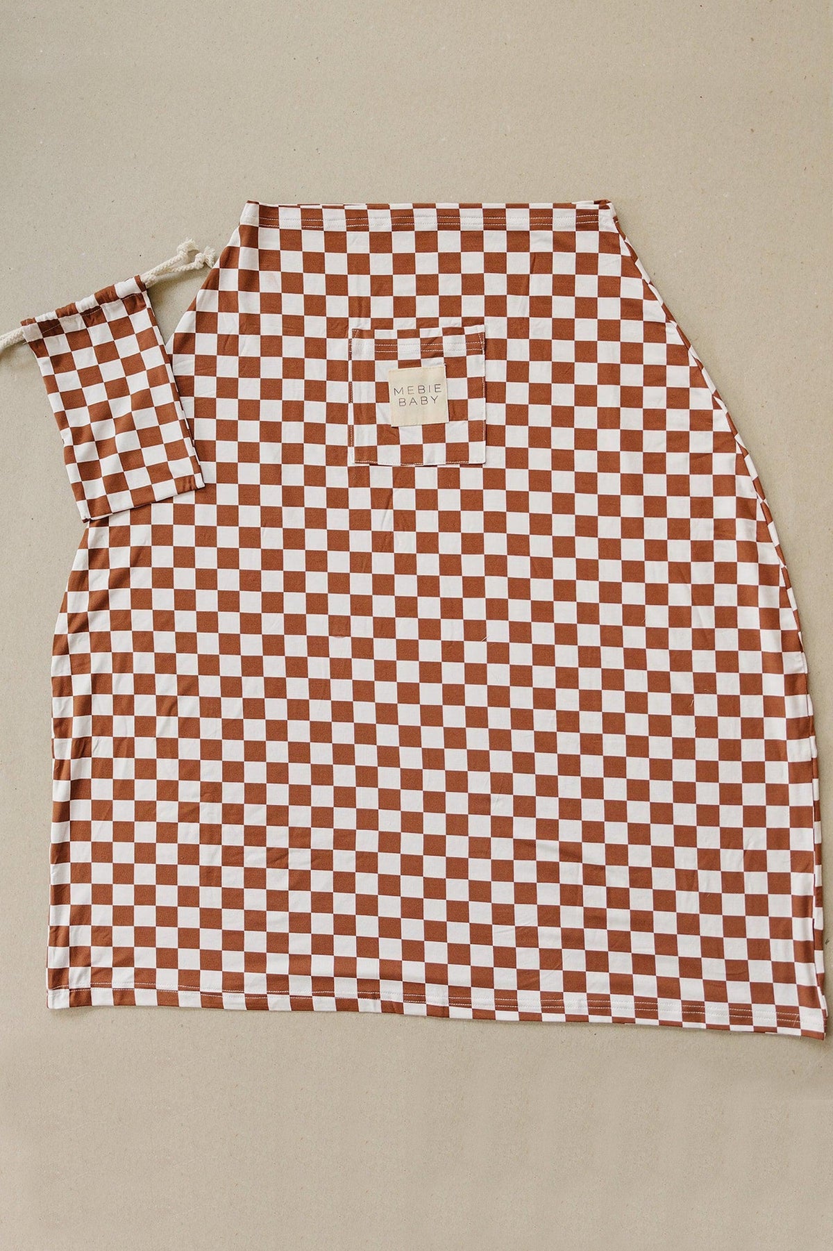 Rust and white checkered bamboo cover with a Mebie Baby label, featuring a drawstring pouch.