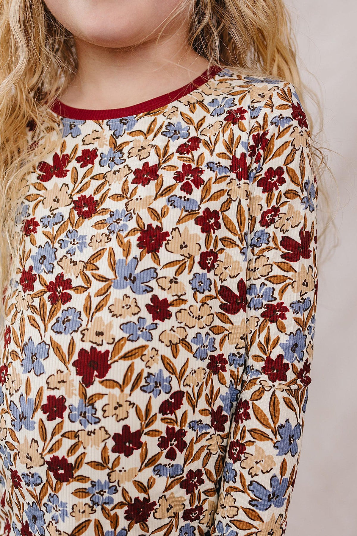Child wearing a ribbed bamboo top with a floral pattern in red and blue, featuring long sleeves and a burgundy.