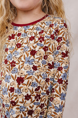Child wearing a ribbed bamboo top with a floral pattern in red and blue, featuring long sleeves and a burgundy.