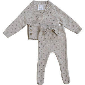 A soft, taupe pointelle knit baby set featuring a wrap-style cardigan with wooden buttons and matching pants. Made from breathable cotton, its designed for comfort and style for little ones.