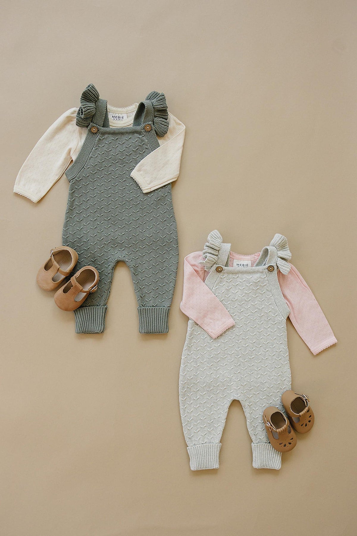 Two sets of baby knit overalls with ruffle details, one grey and one light grey, paired with coordinating shoes.