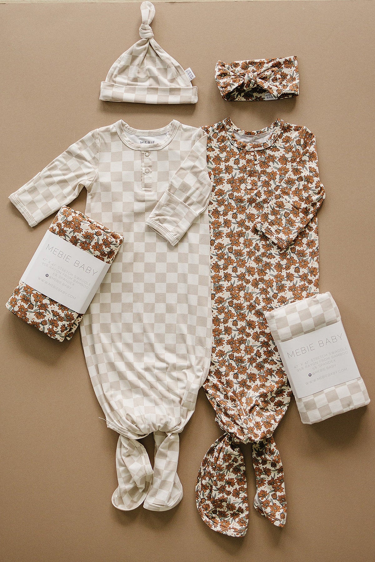 Two Mebie Baby gowns, one taupe checkered and one floral, with matching hats and swaddles on a beige background.