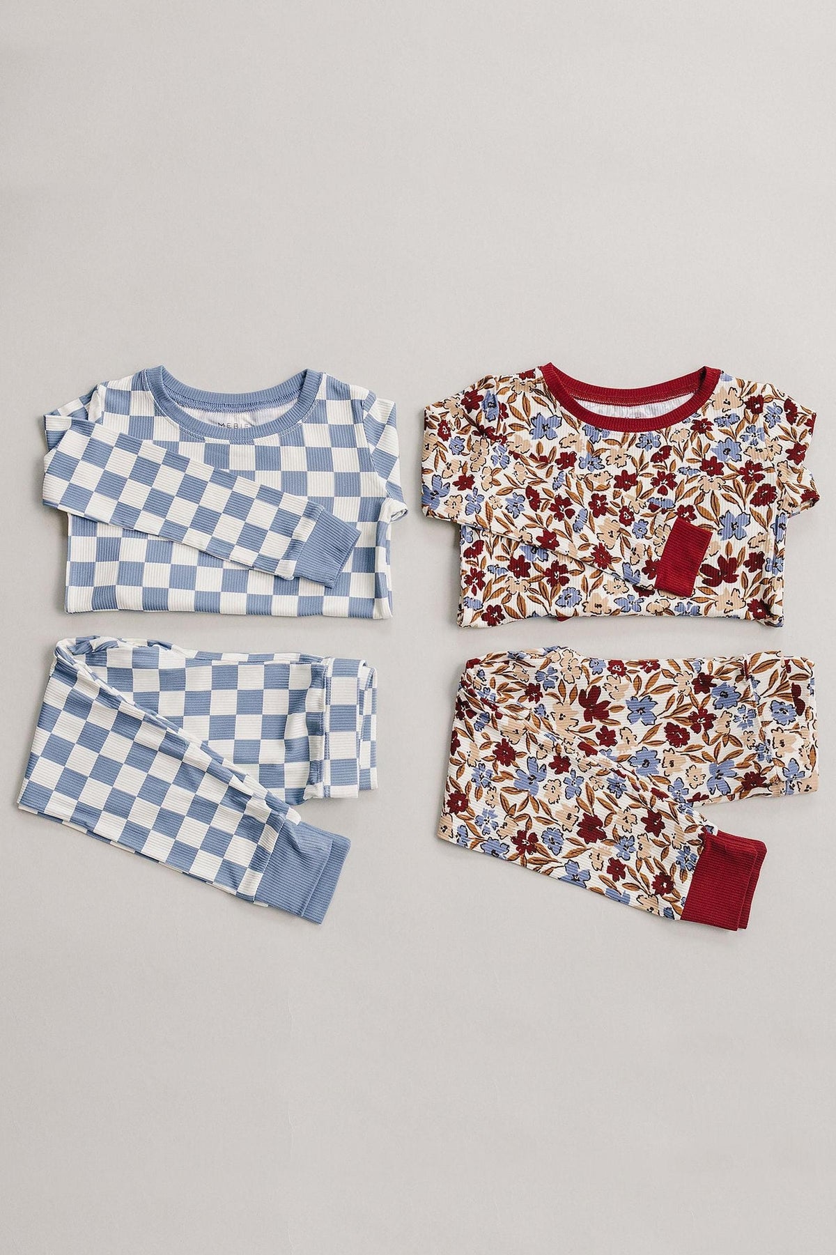 Two childrens clothing sets on a neutral background: one blue checkered, the other floral with red accents.