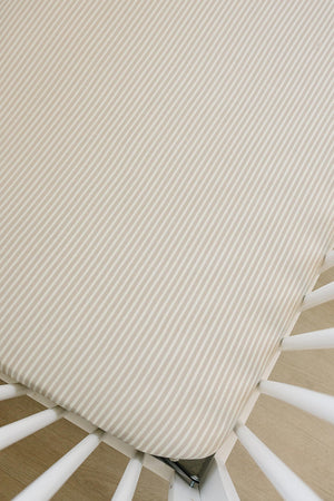 Taupe striped ribbed crib sheet fits snugly on a white crib mattress, showcasing a soft bamboo fabric texture.
