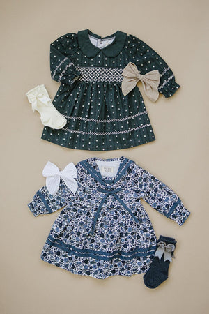 Two floral long-sleeve dresses with bows and matching socks on a beige background, featuring intricate patterns and collars.