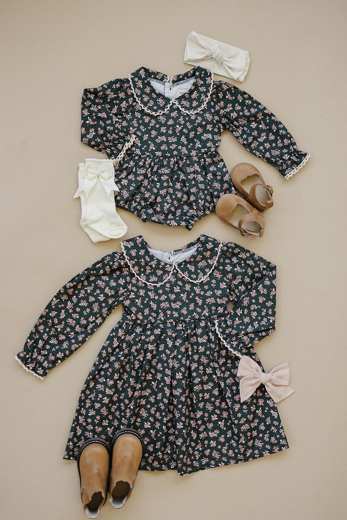 Two floral dresses with Peter Pan collars, matching shoes, bows, and socks on a beige background.