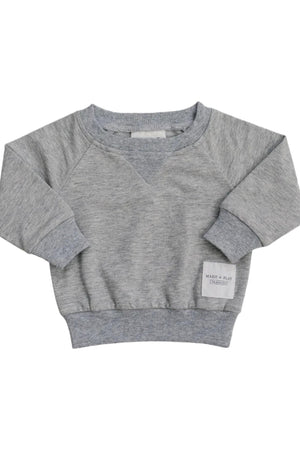 A soft grey cotton crewneck sweatshirt featuring a ribbed neckline and cuffs. It has a small Made + Play label, perfect for kids everyday adventures and comfortable wear.