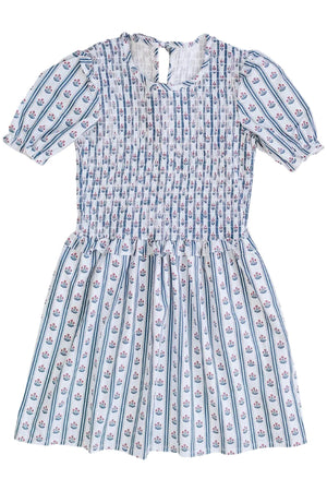 A cotton dress featuring a delicate floral block print in shades of blue and pink, with a smocked bodice and short puff sleeves, suitable for children. Perfect for casual outings.