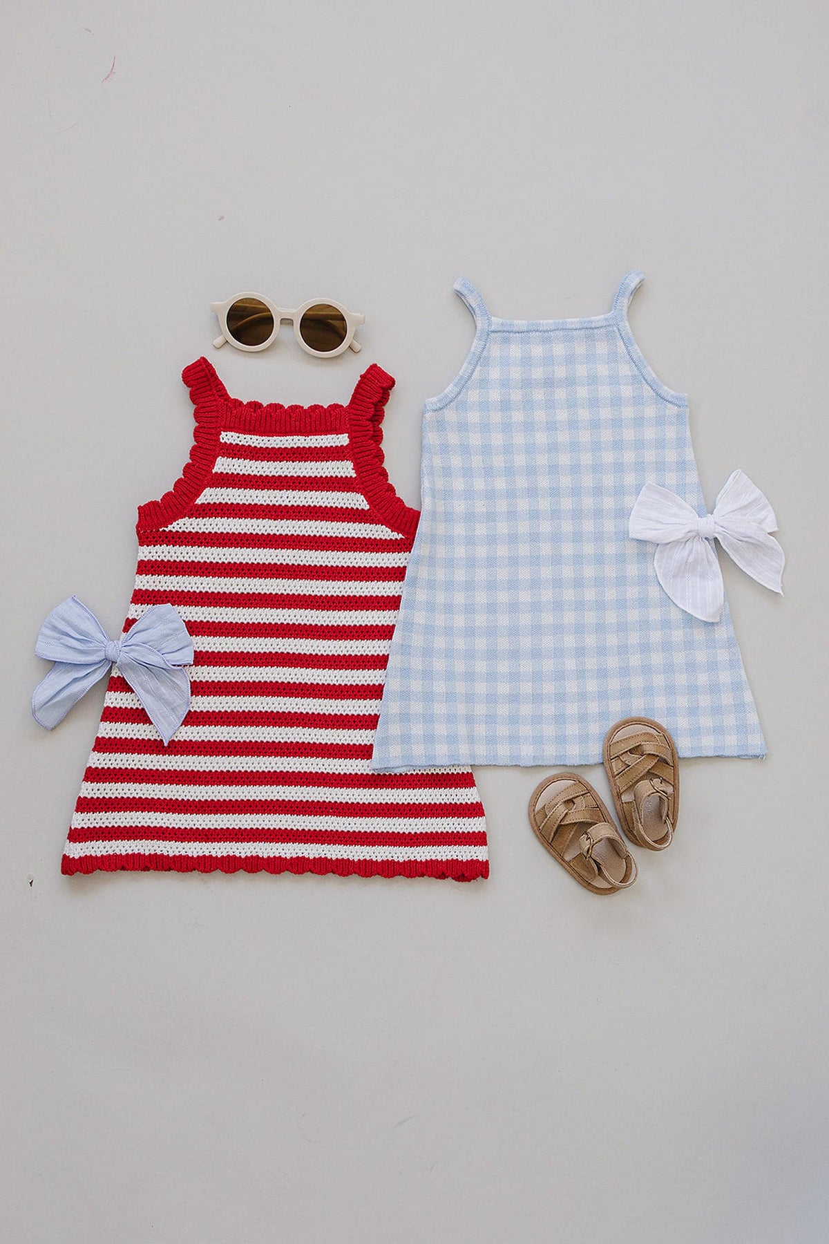 Two childrens dresses are displayed: a red and white striped knit dress with a bow, and a light blue gingham.
