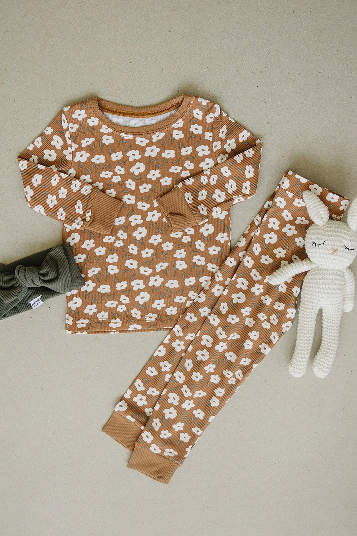 A mustard floral pajama set for babies features a long-sleeve top and matching pants, made from soft ribbed fabric.