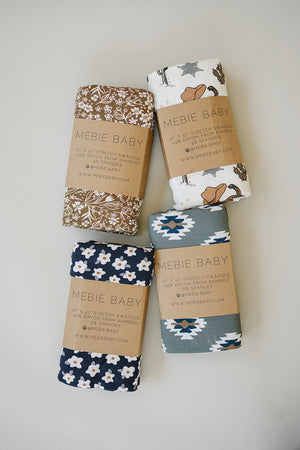 Four rolled swaddles from Mebie Baby, featuring patterns in navy, brown, and gray, showcasing soft bamboo fabric.