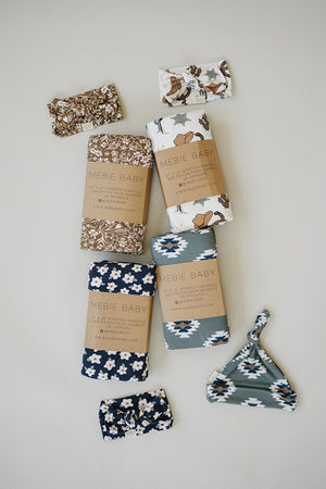 Assorted Mebie Baby swaddles and head wraps in floral and geometric patterns, made from bamboo fabric.