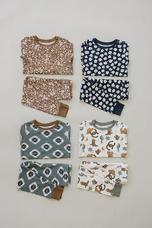 Four folded pajama sets with floral, geometric, and western patterns in brown, navy, and green color schemes.