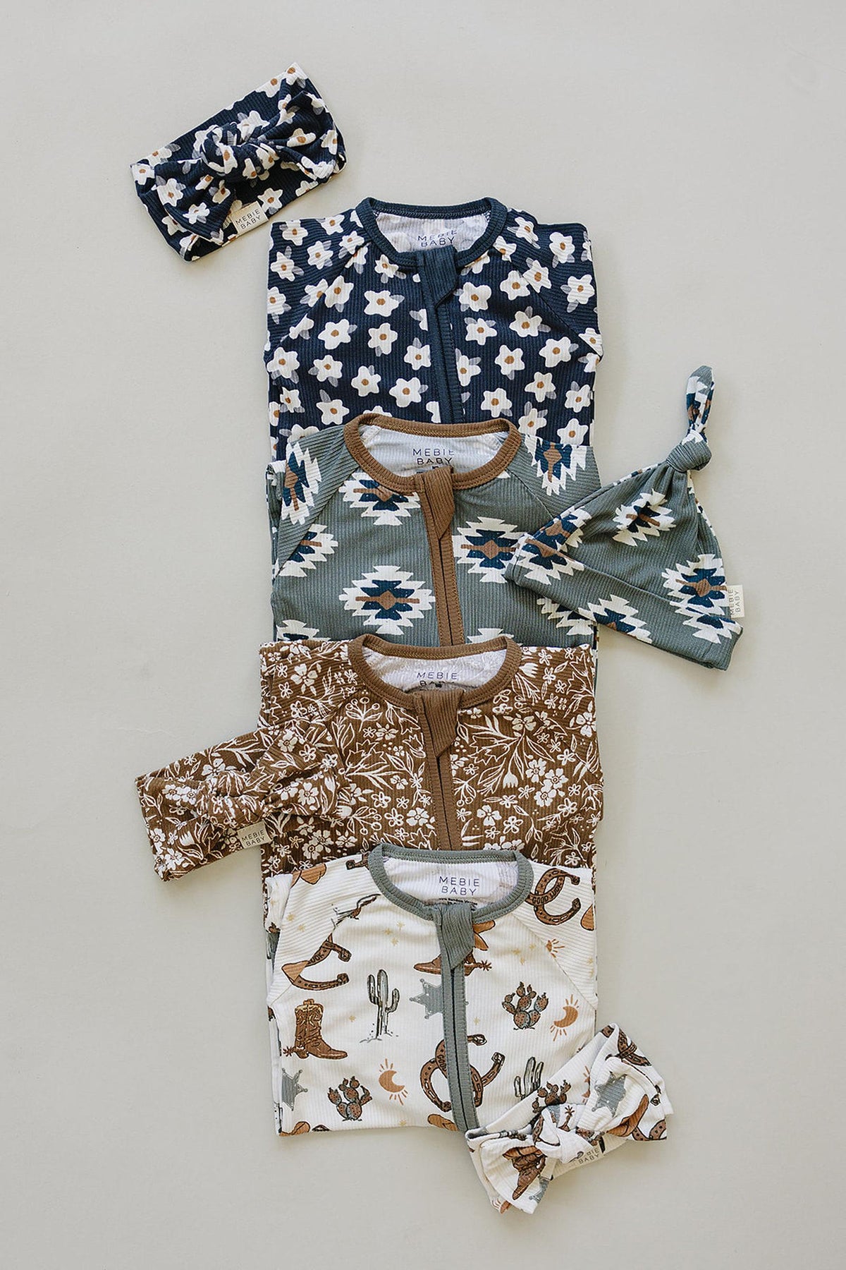 Four sets of Mebie Baby pajamas in various patterns with matching headbands, displayed on a neutral background.
