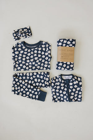 Navy blue childrens pajama set with white daisy pattern, including a top, pants, and matching accessories.