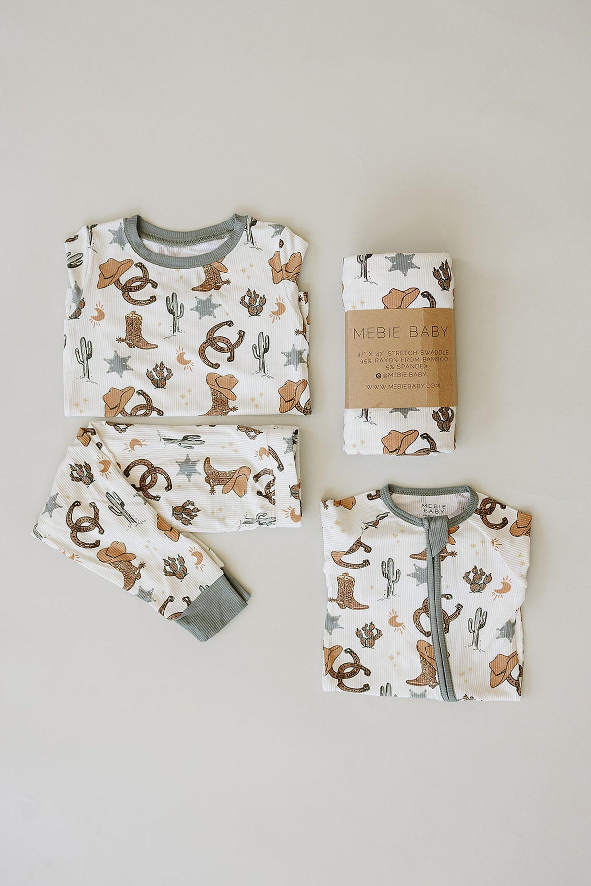 Mebie Baby cowboy-themed bamboo zipper pajamas in a neutral color palette, featuring playful rodeo illustrations, folded with matching pants.