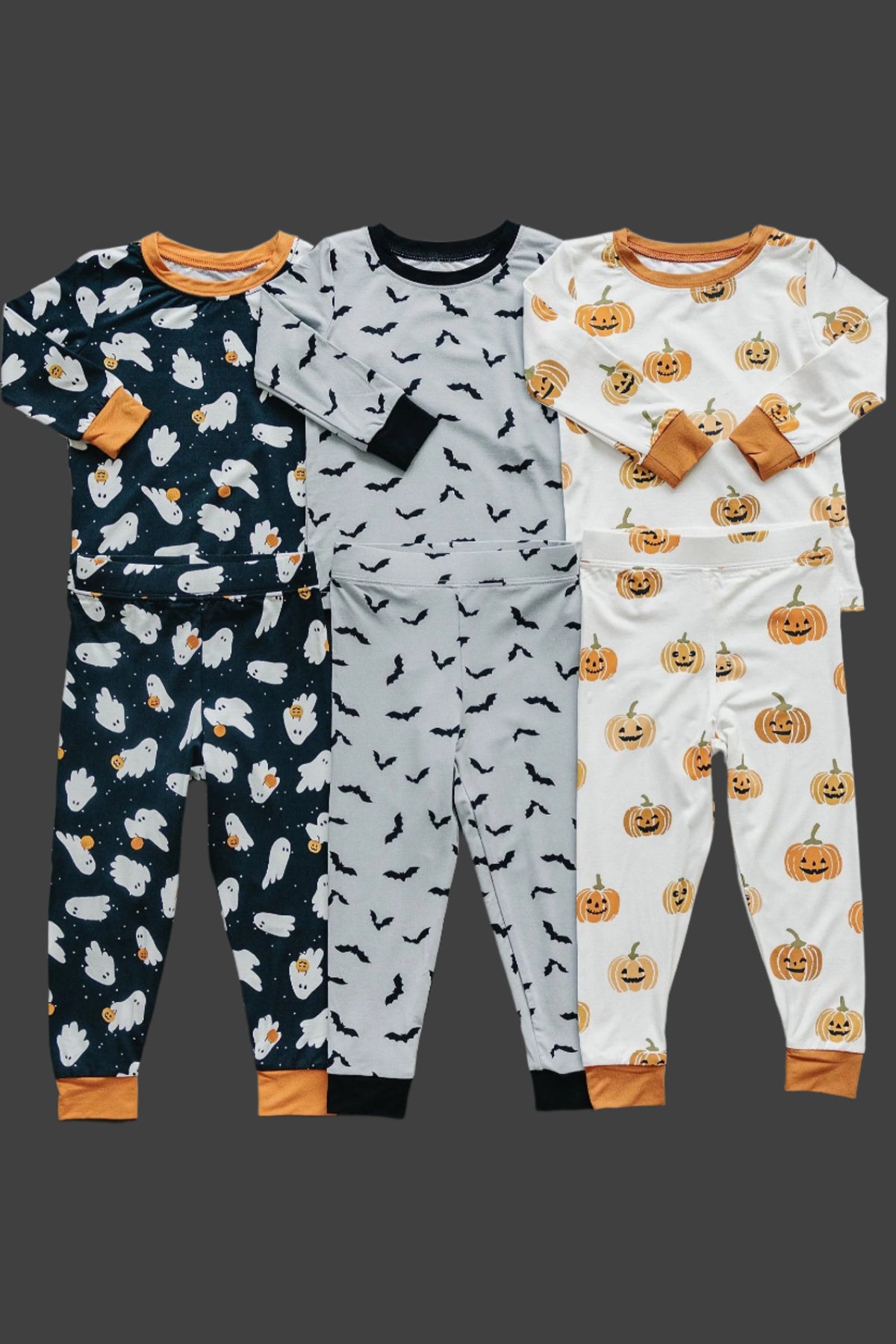 Four sets of Halloween-themed pajamas featuring ghost, bat, and pumpkin prints, in various colors with orange cuffs.