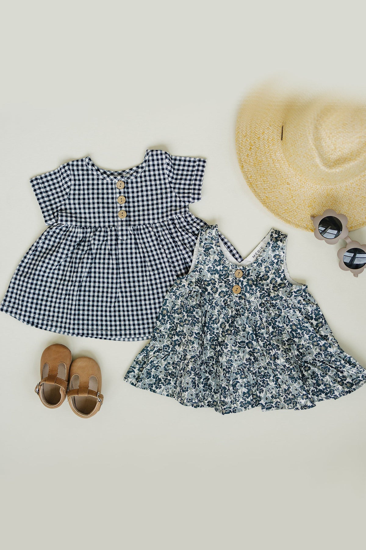 Two adorable dresses are displayed on a light background: a navy gingham dress with buttons and a floral dress.