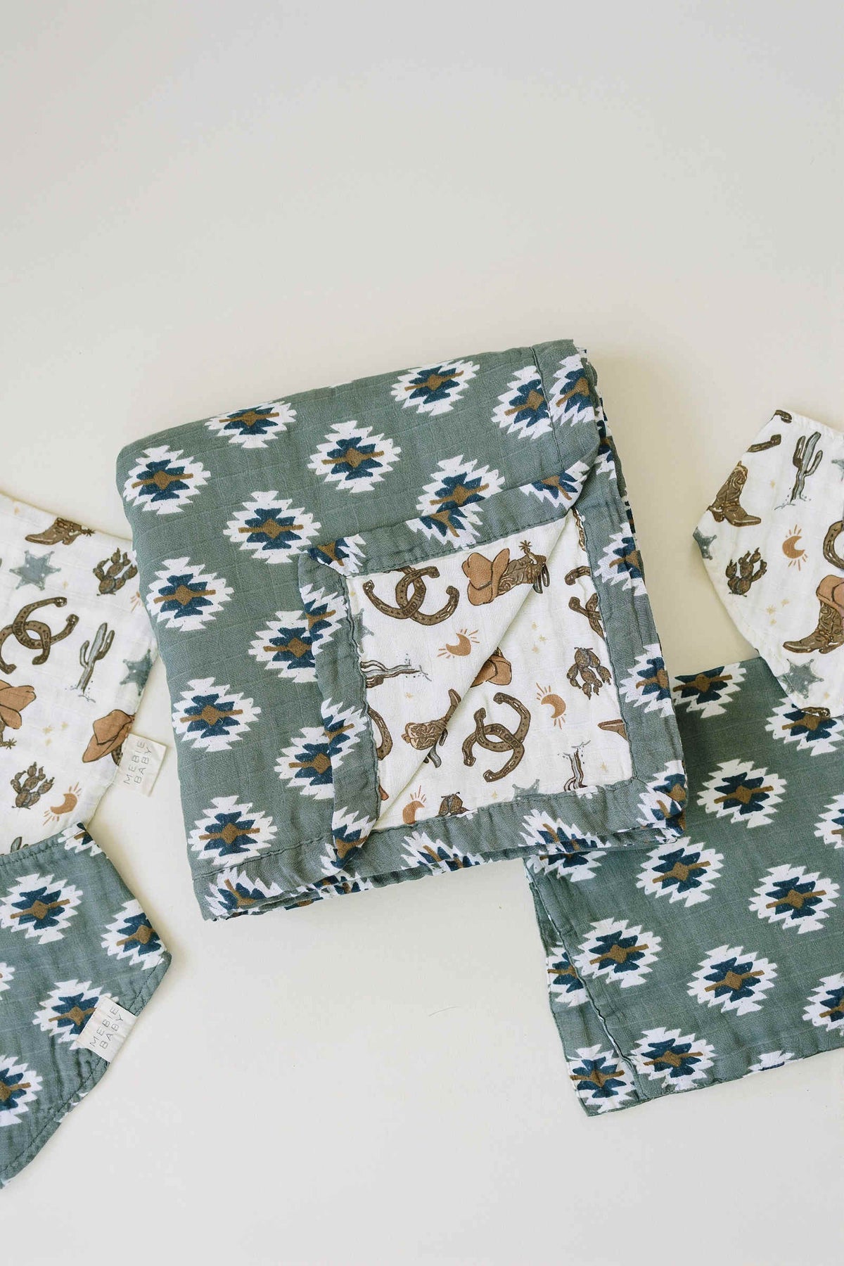 Folded quilt with a Southwest Aztec pattern in neutral colors, featuring cowboy-themed illustrations on the reverse.