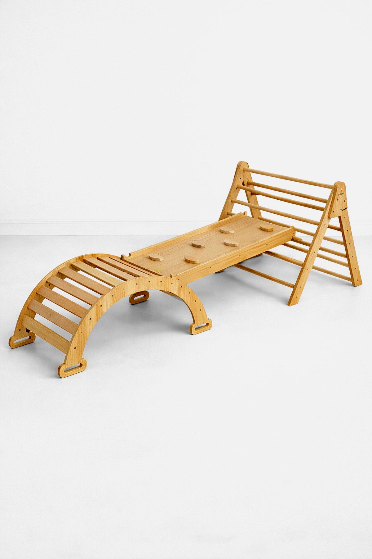 A wooden Pikler triangle playset in a natural finish features a climbing structure and slide. It is designed for toddlers, promoting active play and imaginative exploration in a safe environment.