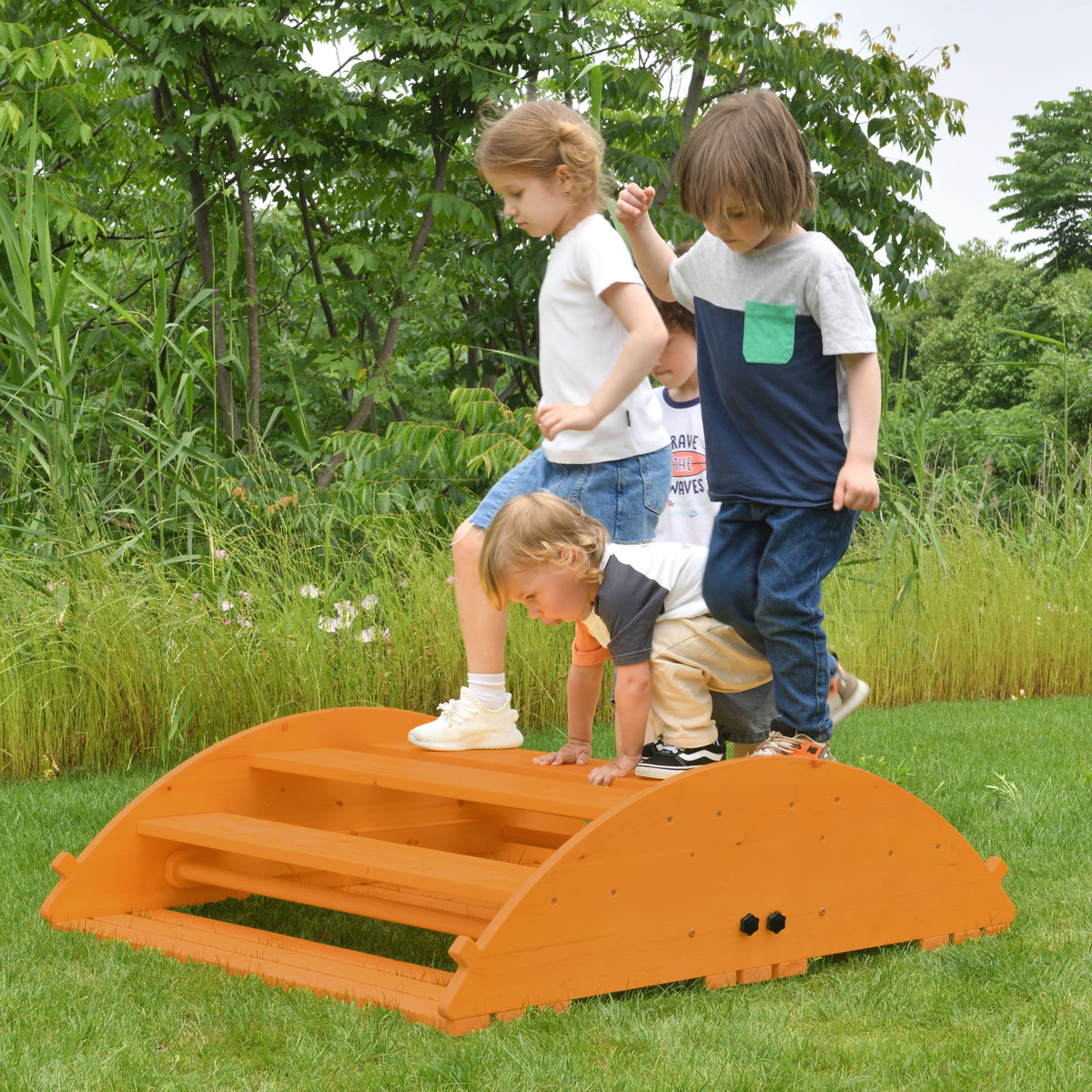 Four children play on a bright orange wooden climbing structure in a grassy outdoor setting. The sturdy design encourages active play, featuring steps and a rounded top for climbing and.