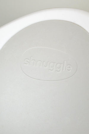 Close-up of a white Shnuggle product surface with embossed logo, showcasing simple and clean design aesthetics.