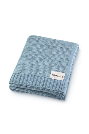 Light blue knit blanket folded neatly, featuring a Bleu-La-La label. Made from organic cotton, perfect for babies.