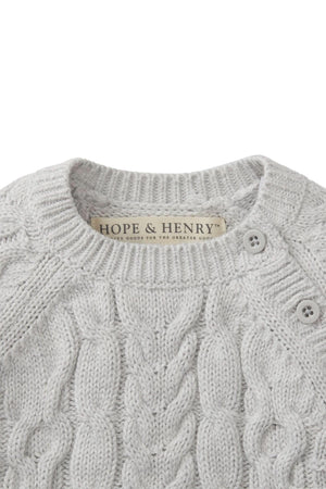 Close-up of a light gray cable knit sweater romper by Hope & Henry, showcasing soft organic cotton fabric and button openings at the shoulder. Perfect for babies aged 0-24 months.