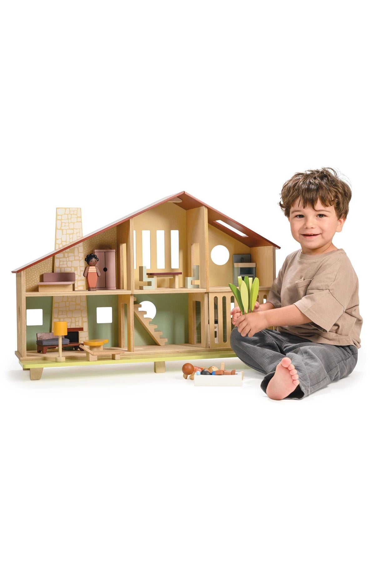 A child plays with a wooden Mentari dollhouse featuring a retro-modern design and colorful furniture pieces.