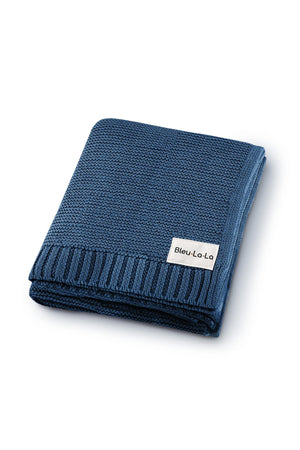 Folded blue knit blanket with a ribbed edge and a Bleu-La-La label, made from organic cotton.