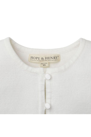 Close-up of a white cardigan by Hope & Henry featuring a round neckline and pearlized button closure.