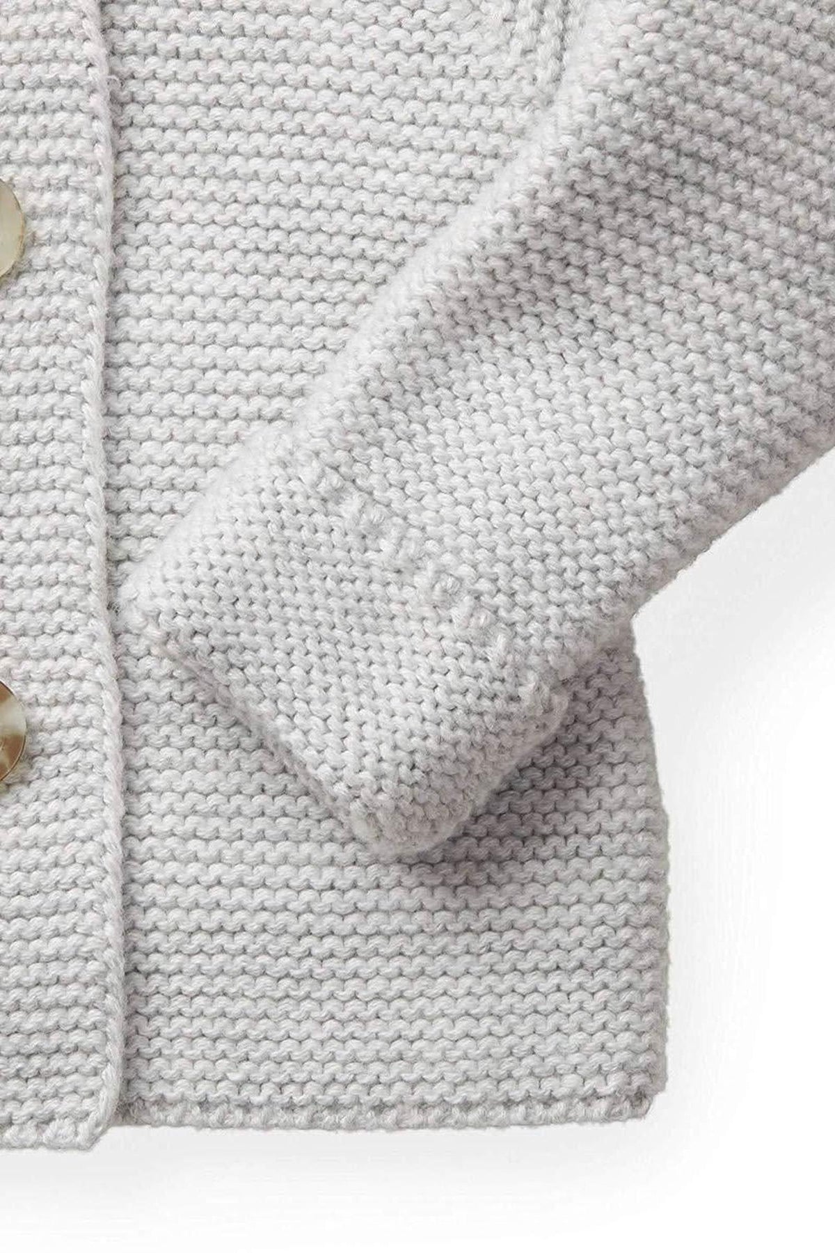 Light gray organic cotton sweater featuring a textured seed stitch and a cozy fit. The design includes a faux fur trim and stylish button details, perfect for babies.