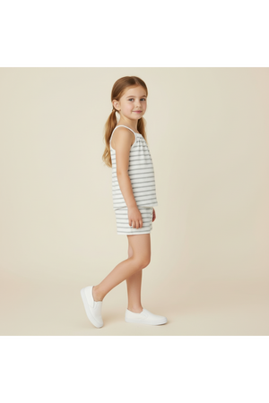 A young girl stands in profile, wearing a light gray and white striped organic cotton tank top and shorts set.