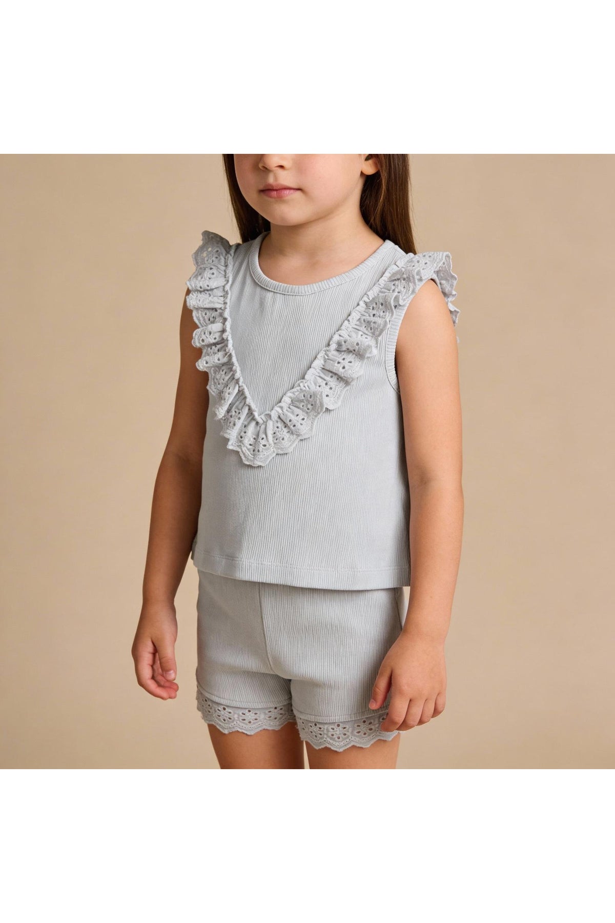 A young girl models a light gray organic cotton ruffle top and shorts set, featuring delicate lace trim.