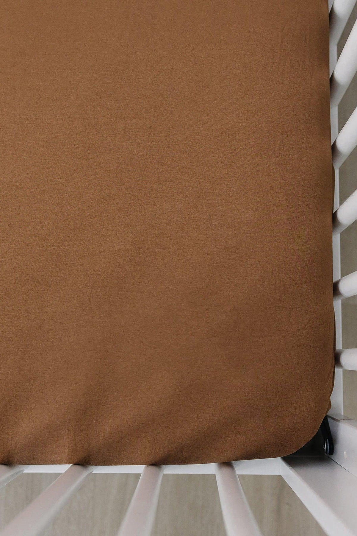 Mustard-colored crib sheet made of bamboo fabric on a white crib, highlighting soft, eco-friendly material.