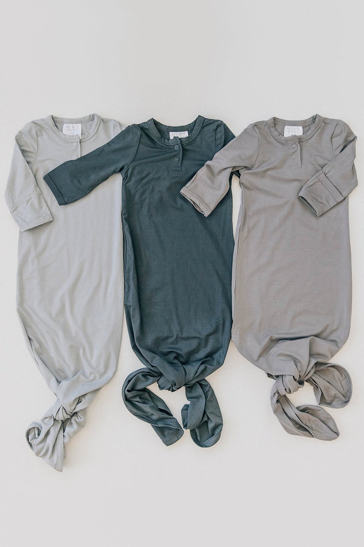 Three gender-neutral baby knot gowns in light gray, dark gray, and medium gray, made from soft bamboo fabric.
