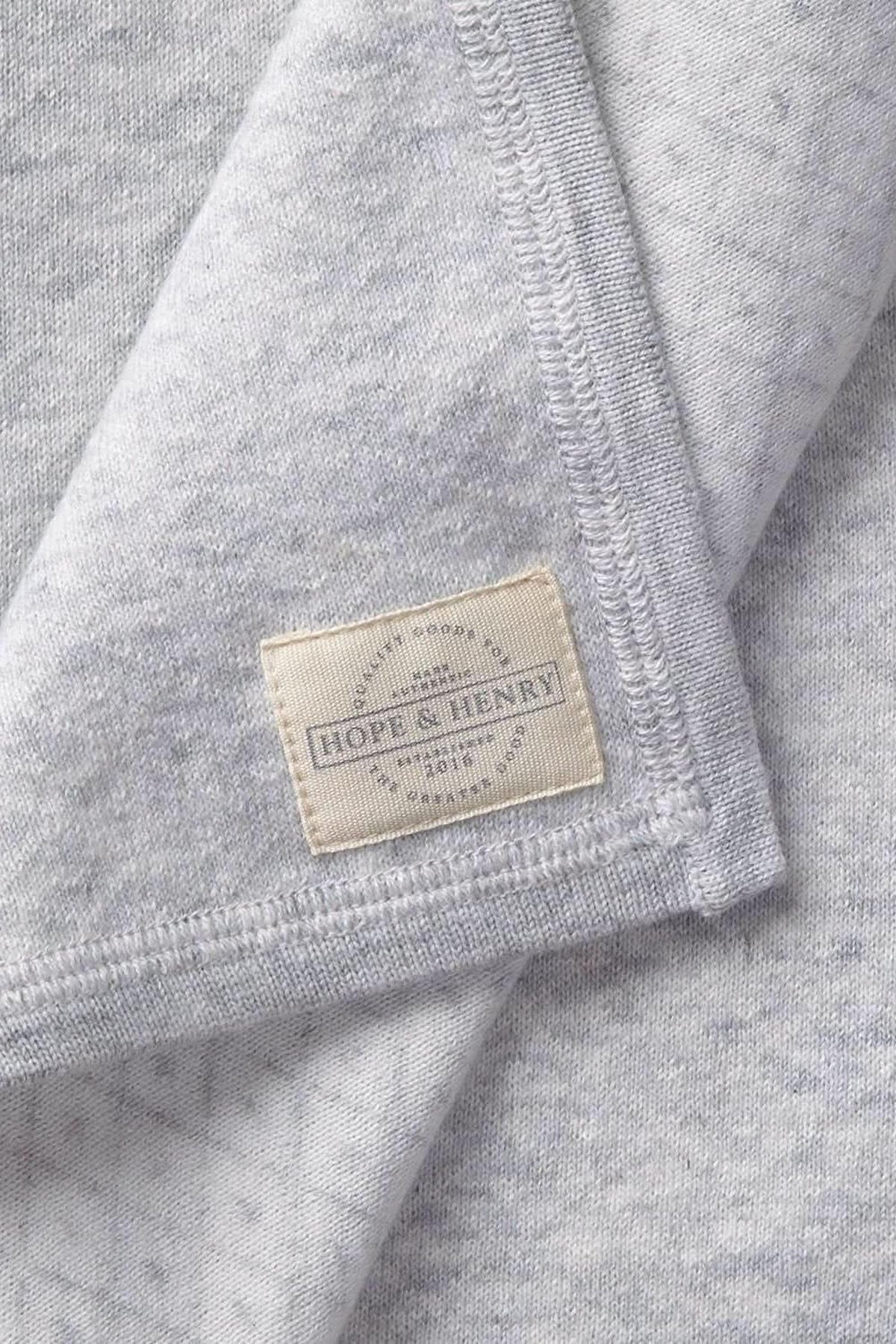 Close-up of a gray organic cotton fabric featuring a subtle diamond pattern, with a visible label reading Hope & Henry. The soft material suggests comfort for babies and toddlers.