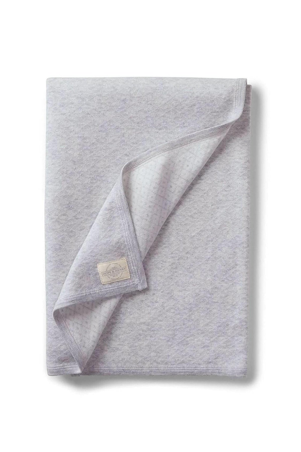 A soft gray blanket made from organic cotton features a subtle jacquard pattern. Ideal for babies, it’s perfect for strollers and outings, showcasing sustainable, family-friendly design.
