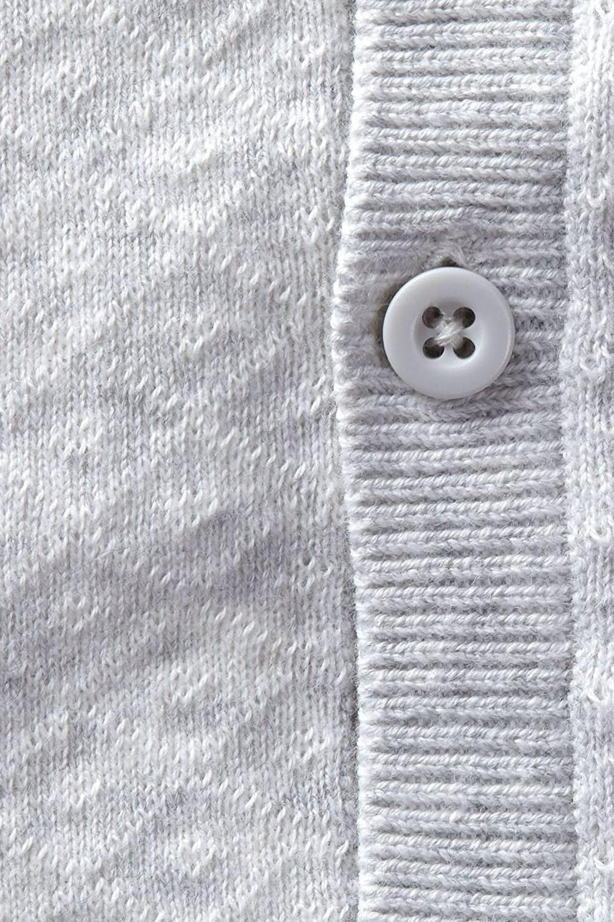 Close-up of a light gray organic cotton sweater romper featuring a button closure and textured knit fabric.
