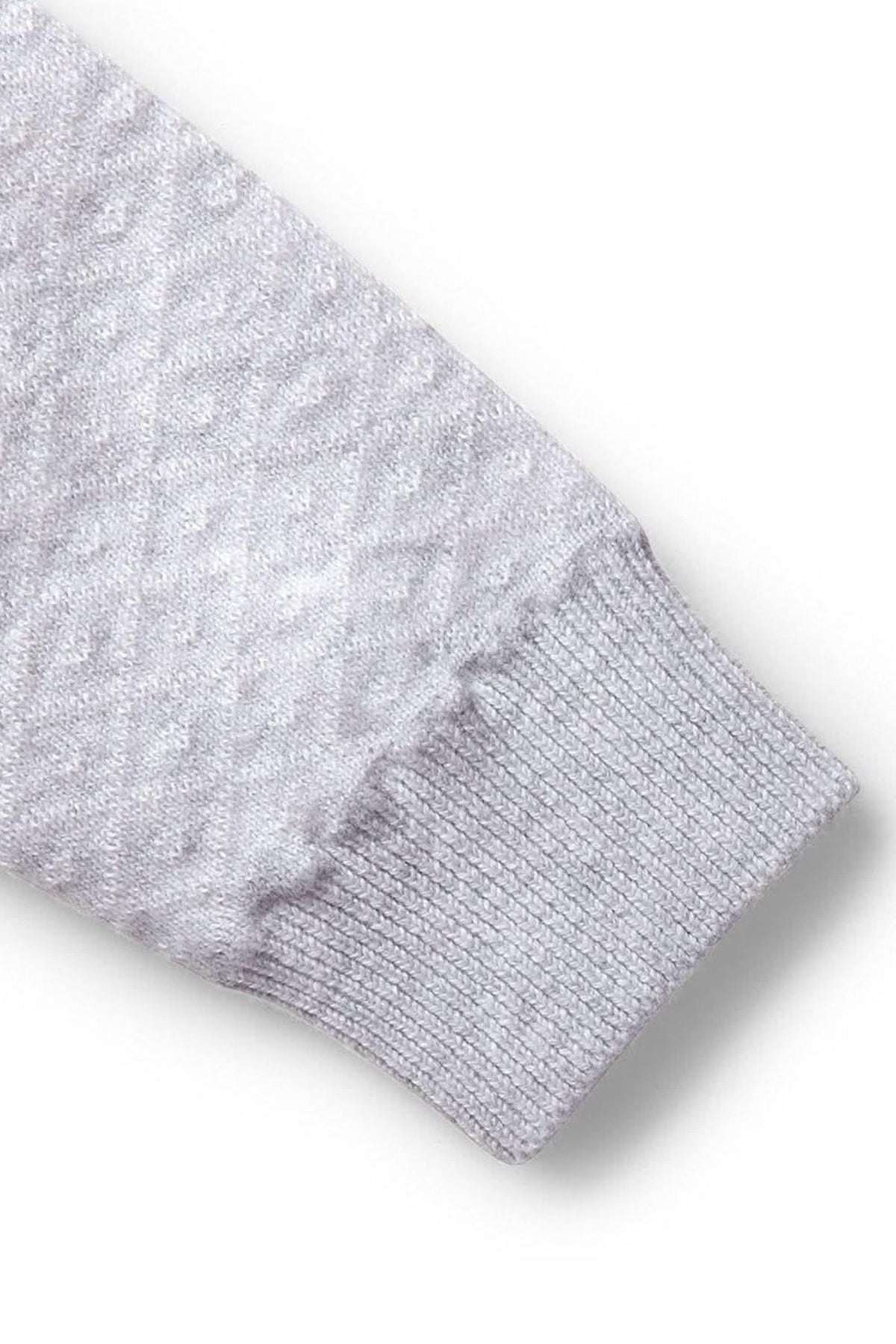 Close-up of a light gray sweater romper sleeve featuring a textured diamond pattern and ribbed cuff, made from organic cotton.